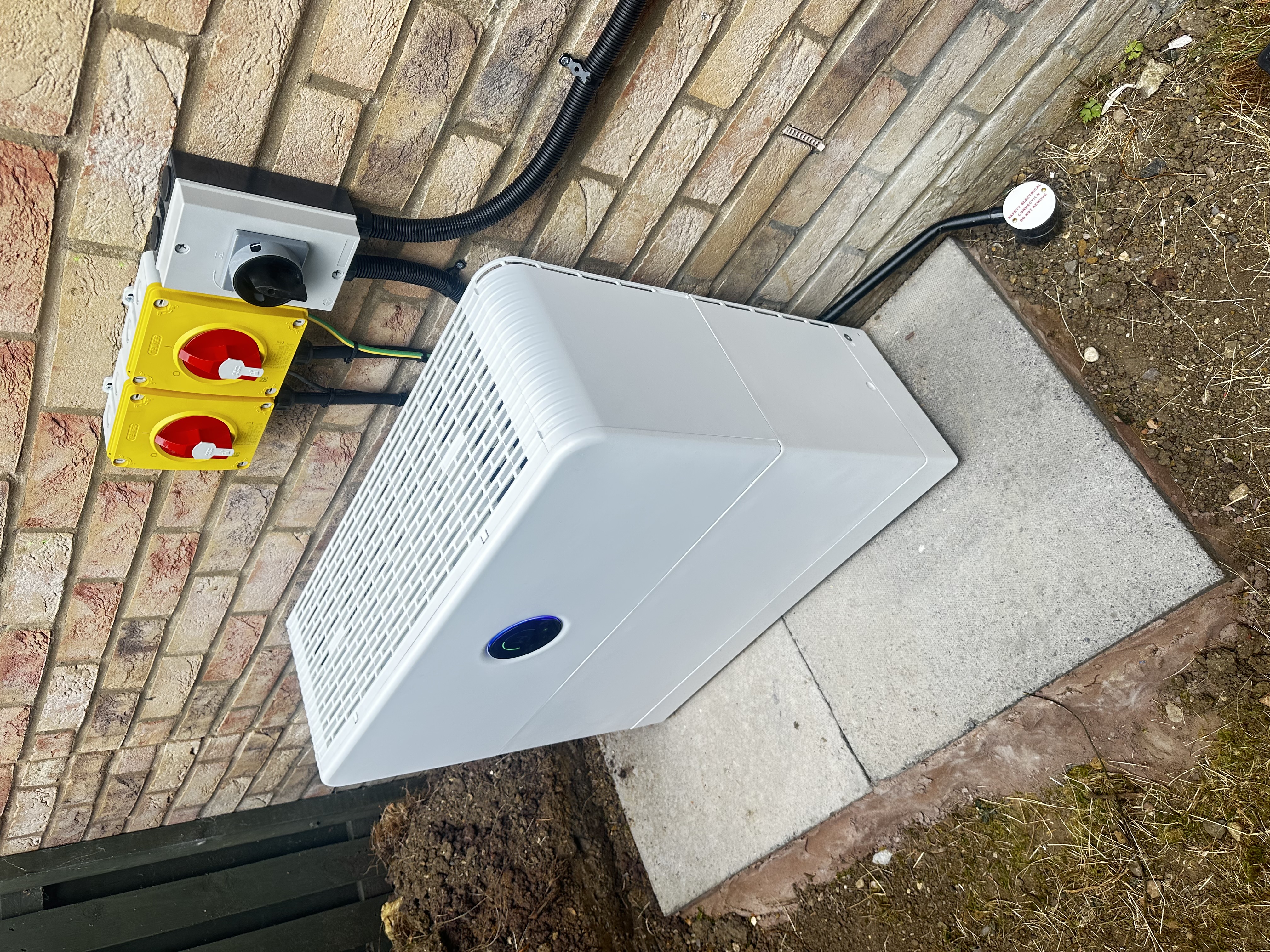 External home battery installation beside a brick wall
